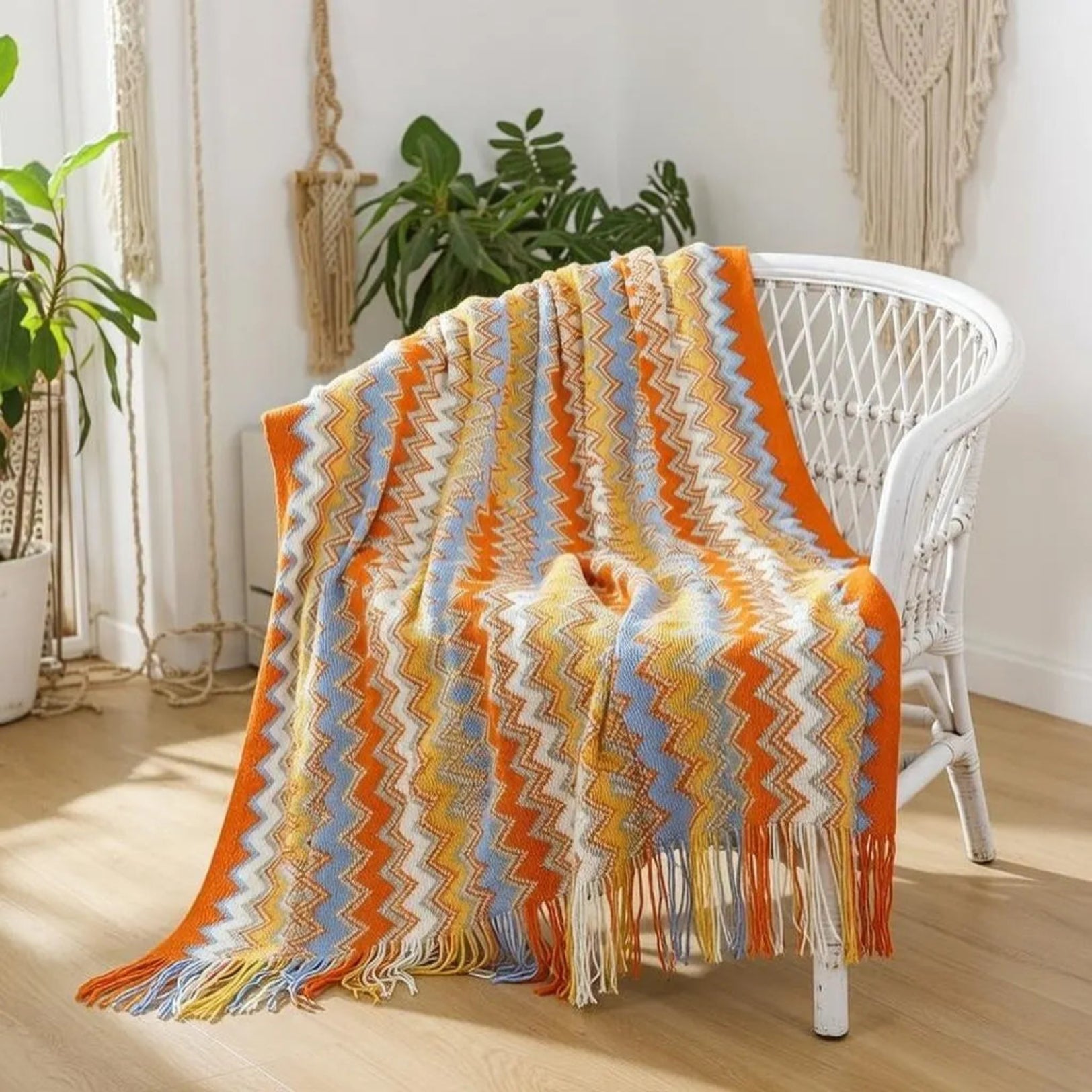 Orange fringed edge blanket draped on white rattan chair, boho decor