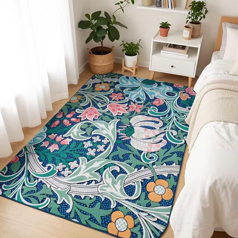 Teal blue William Morris floral area rug placed at the foot of a white bed in a bright bedroom