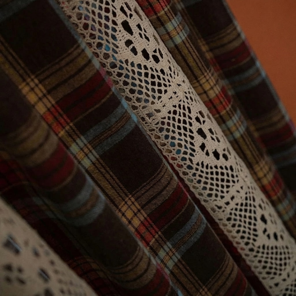 Close-up detail of cream crochet lace band on brown tartan plaid curtain fabric, warm golden backlight