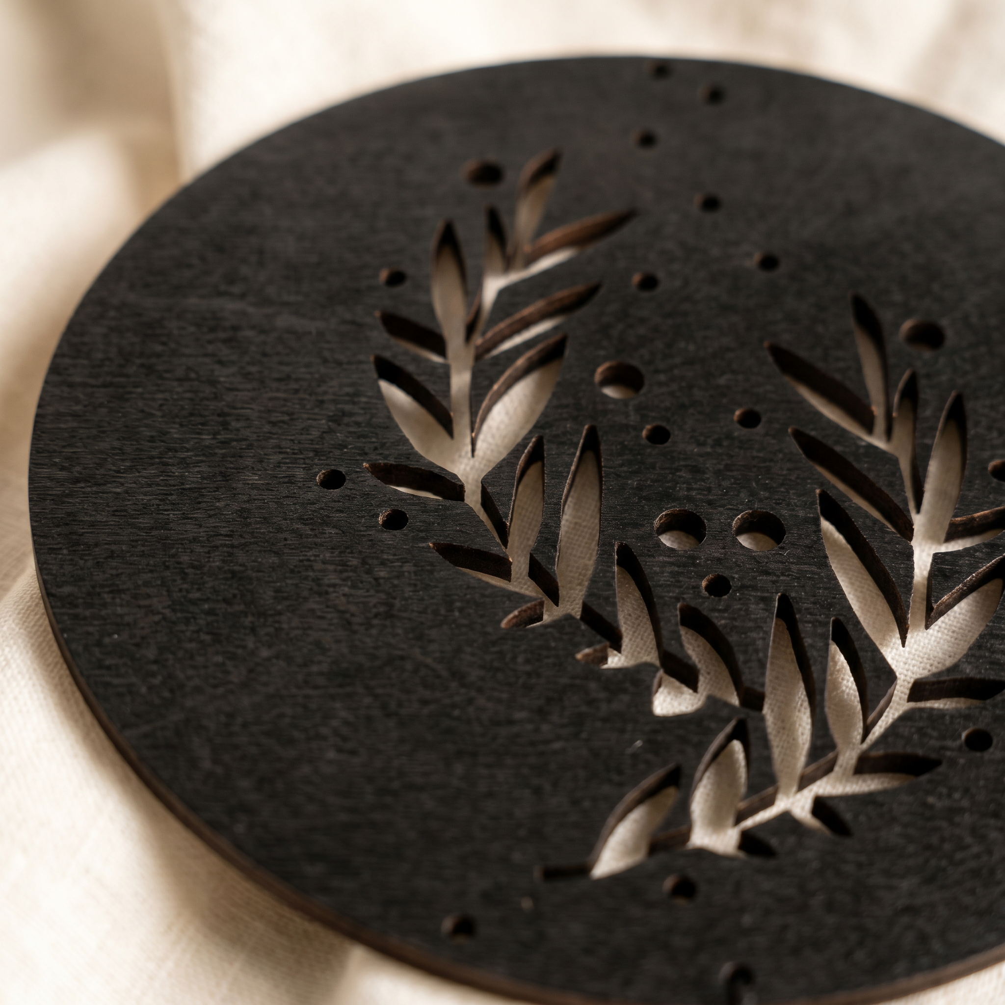 Black wood moon phase pendant — light through laser-cut negative spaces casting shadows on wall