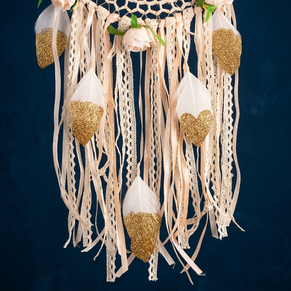 Close-up white feathers gold glitter heart accents and lace ribbon strands bohemian dreamcatcher navy background