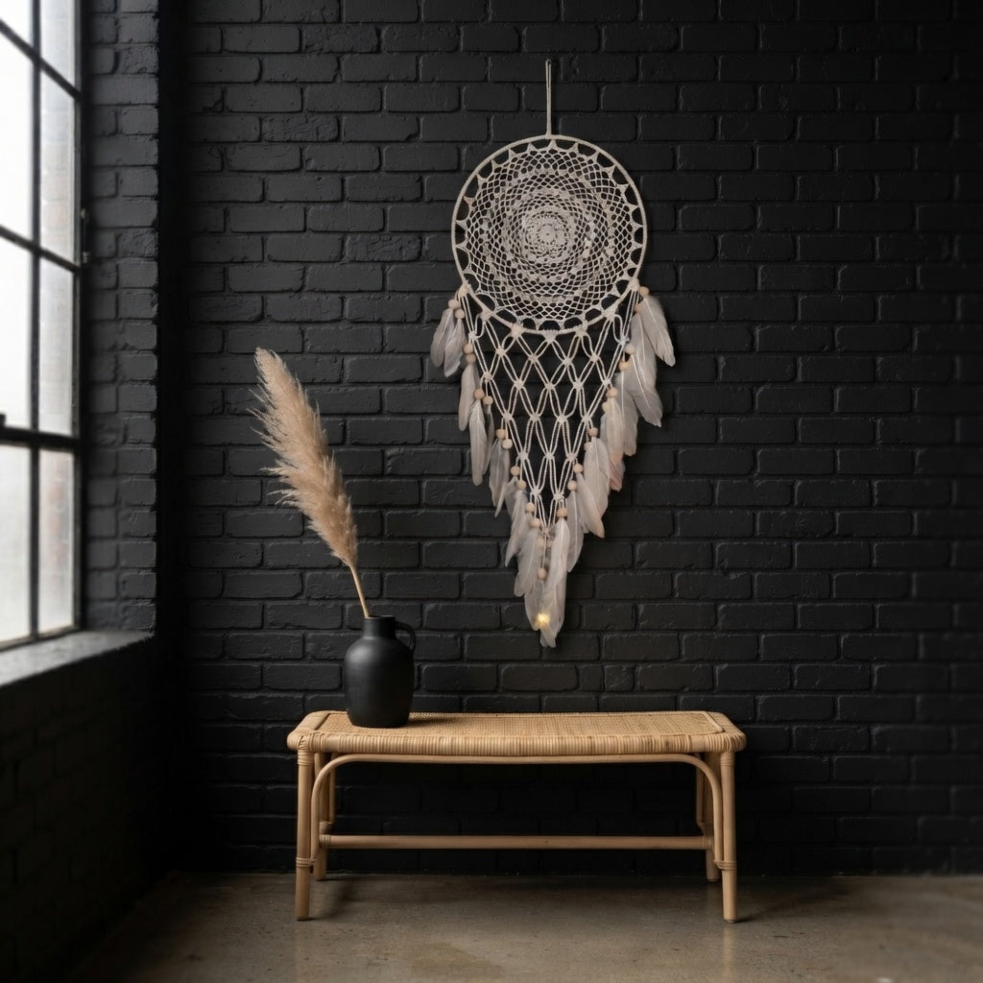 Large boho dreamcatcher with faux feathers hanging on a dark brick accent wall in a modern loft