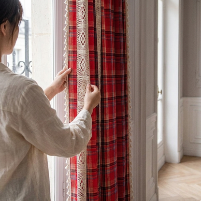 Woman adjusting a red tartan crochet lace curtain at a window, close-up of cream lace band and tassel trim
