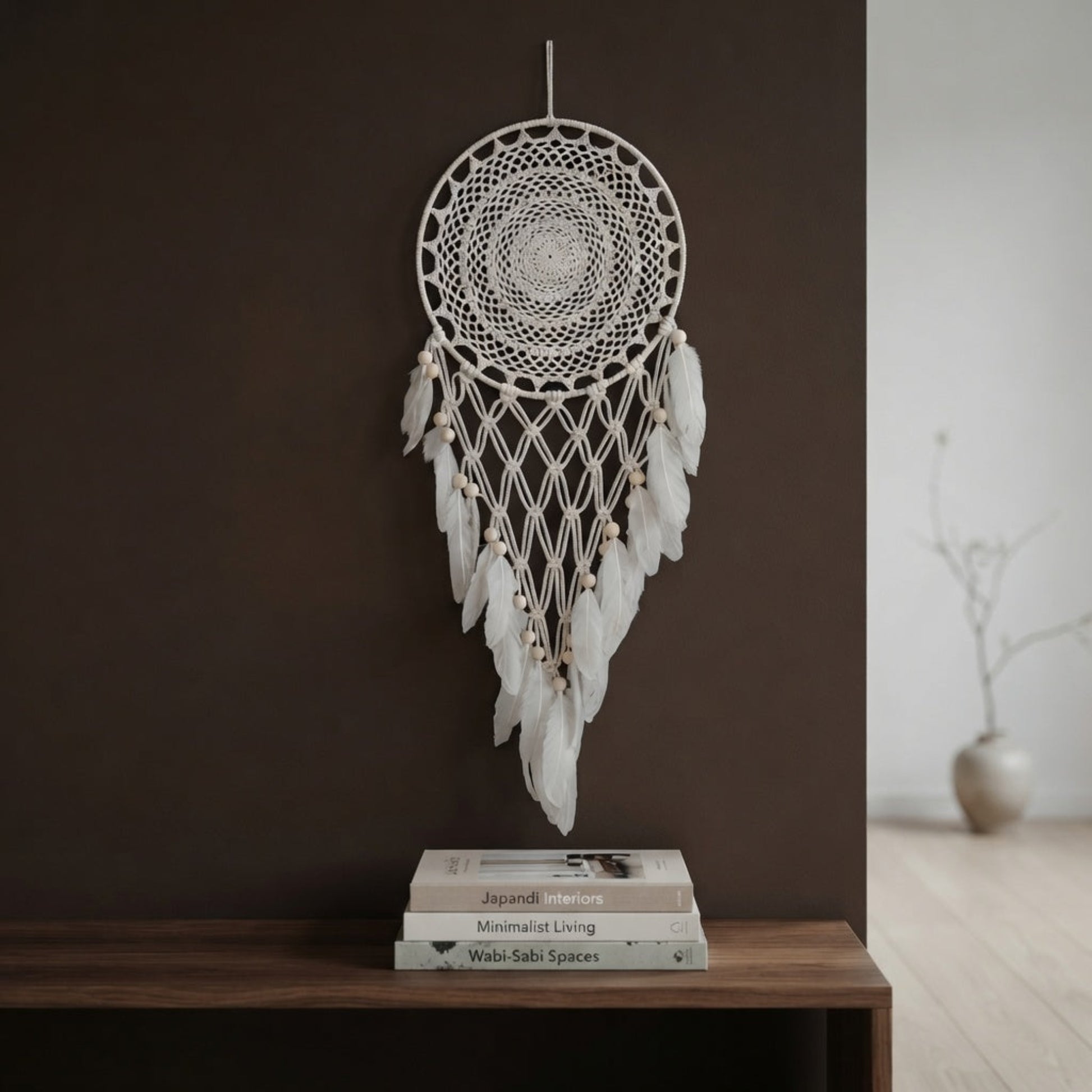Cream crochet dreamcatcher with wood beads displayed above a console table on a brown accent wall