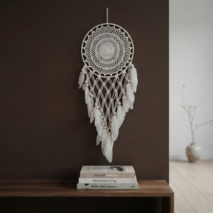 Cream crochet dreamcatcher with wood beads displayed above a console table on a brown accent wall