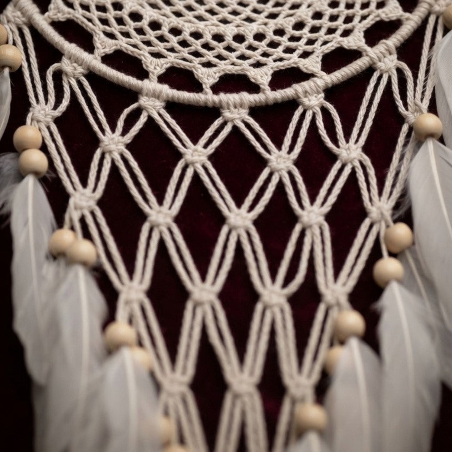 Close-up of macrame netting, wood beads, and faux feathers on a handcrafted boho dreamcatcher