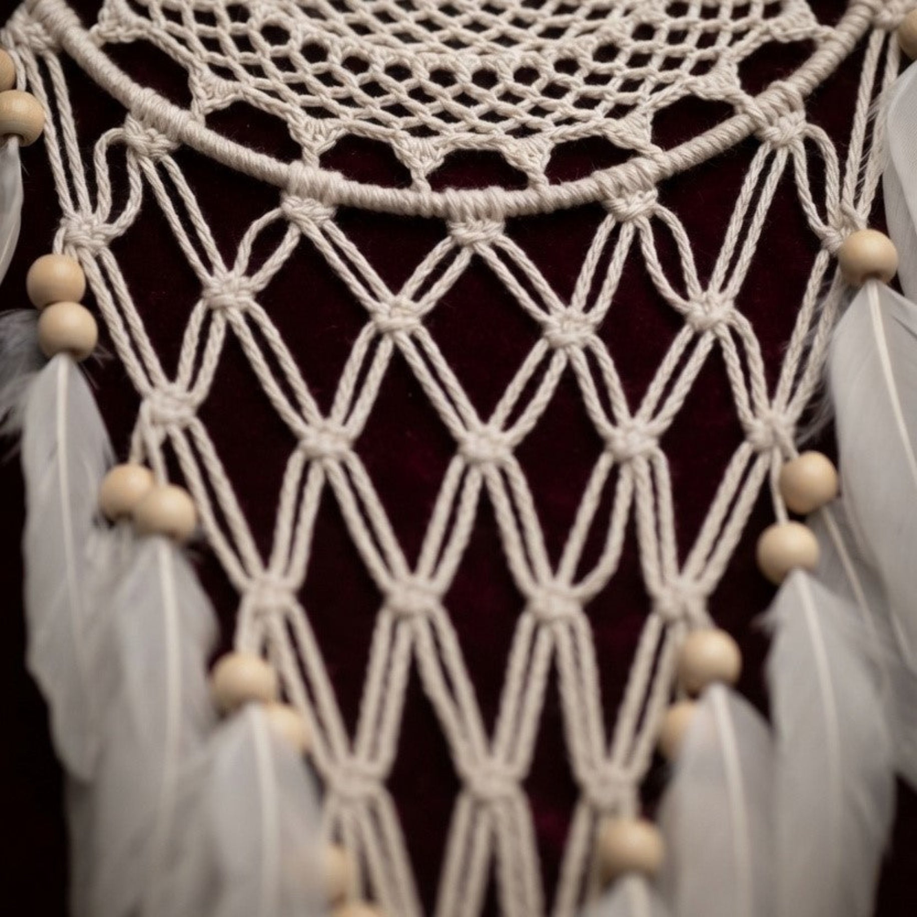 Close-up of macrame netting, wood beads, and faux feathers on a handcrafted boho dreamcatcher