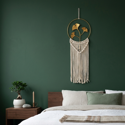 Gold ginkgo leaf macrame wall hanging on deep green wall above low walnut bed in Japandi bedroom — Bohoartis