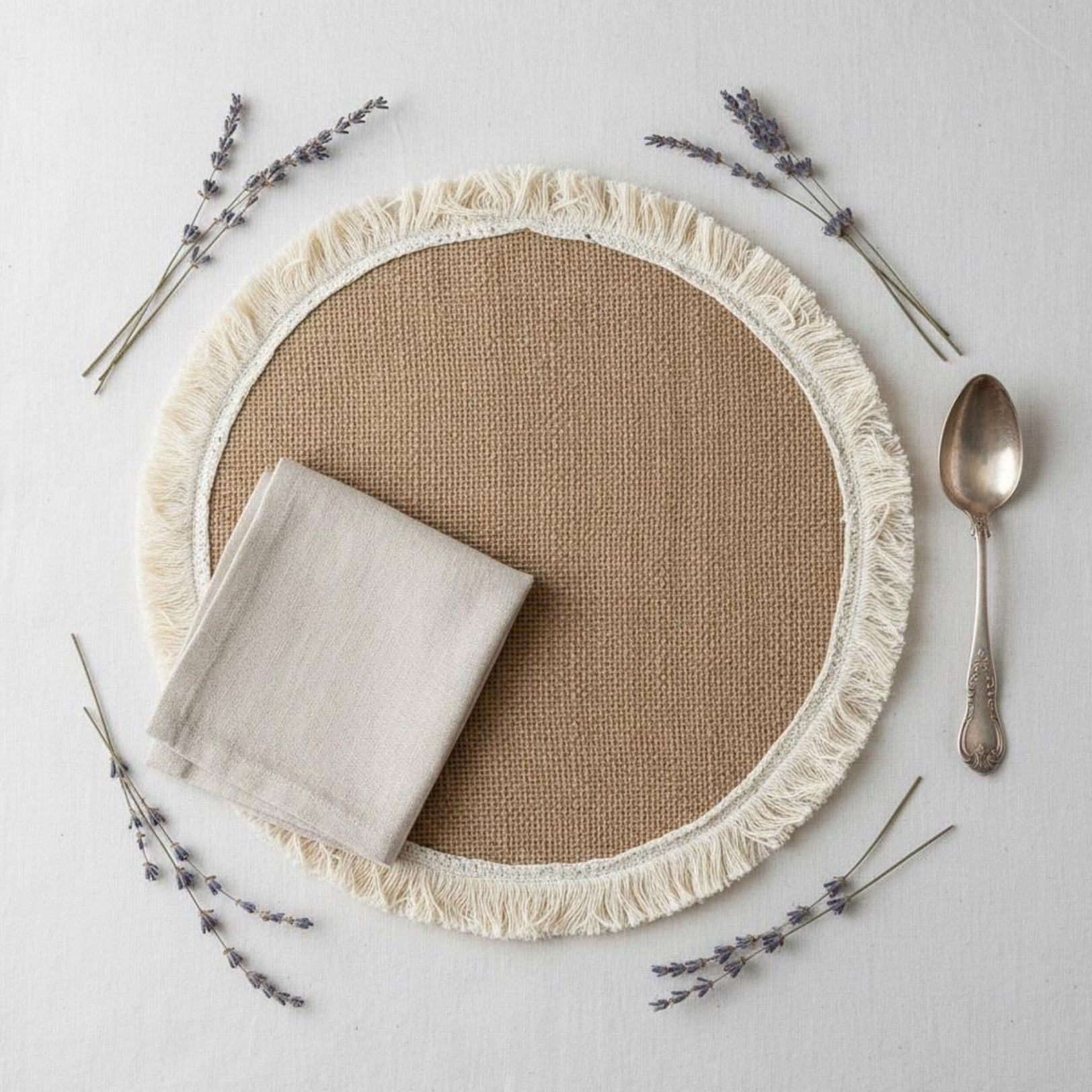 Flat lay of jute placemat with linen napkin and cutlery for farmhouse decor