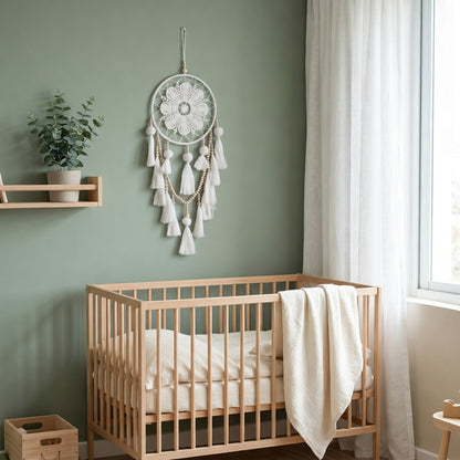 White dream catcher hanging in Scandinavian nursery beside wooden crib — sage green wall decor
