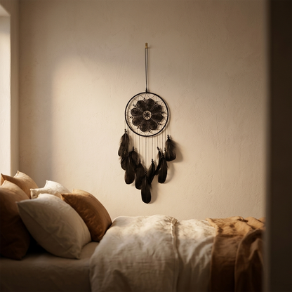 Dreamcatcher hanging on a wall above a bed with pillows and blankets.