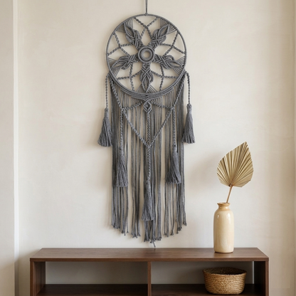 Grey round macrame dreamcatcher on warm white wall above walnut console table in Japandi living room — Bohoartis