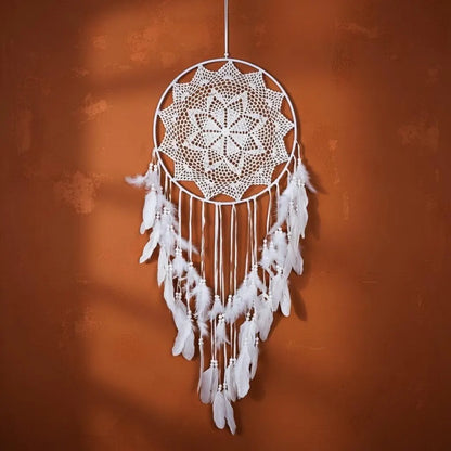 White dreamcatcher with feathers against an orange wall