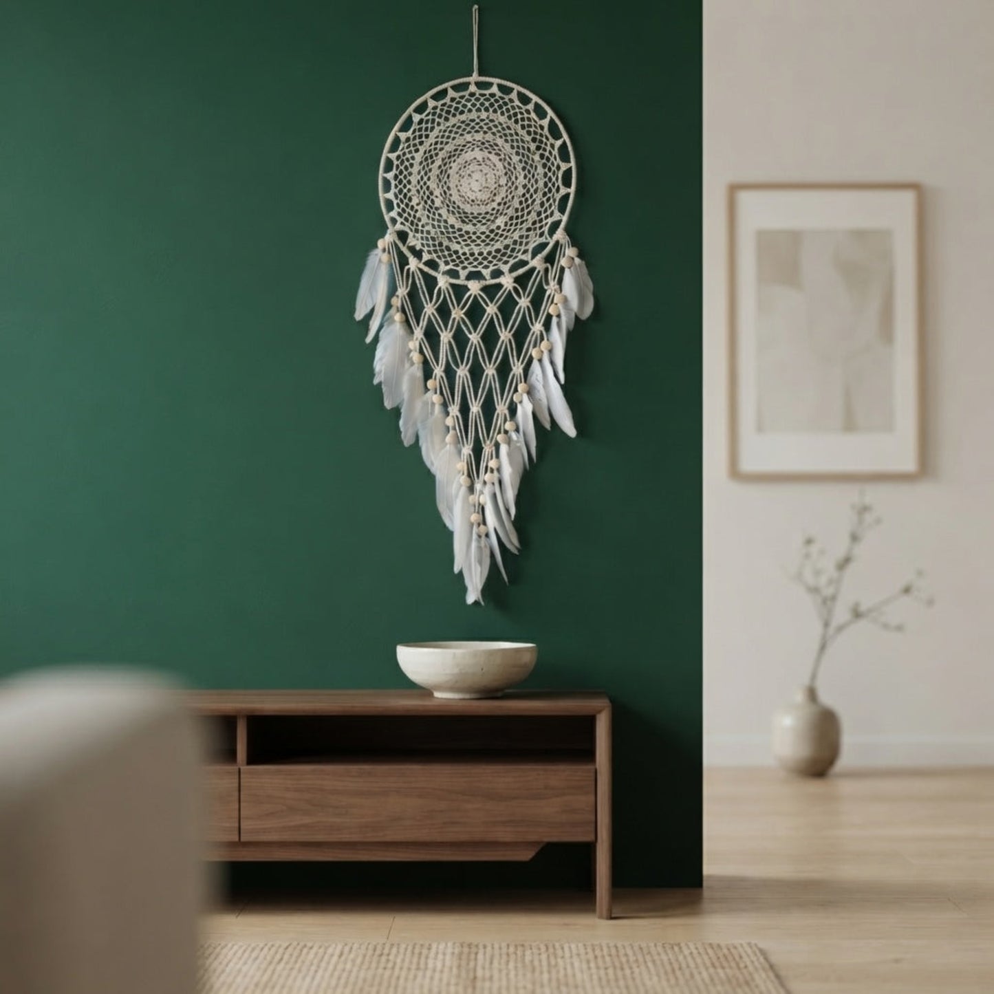 Boho macrame dreamcatcher with faux feather decor mounted on a deep green living room wall