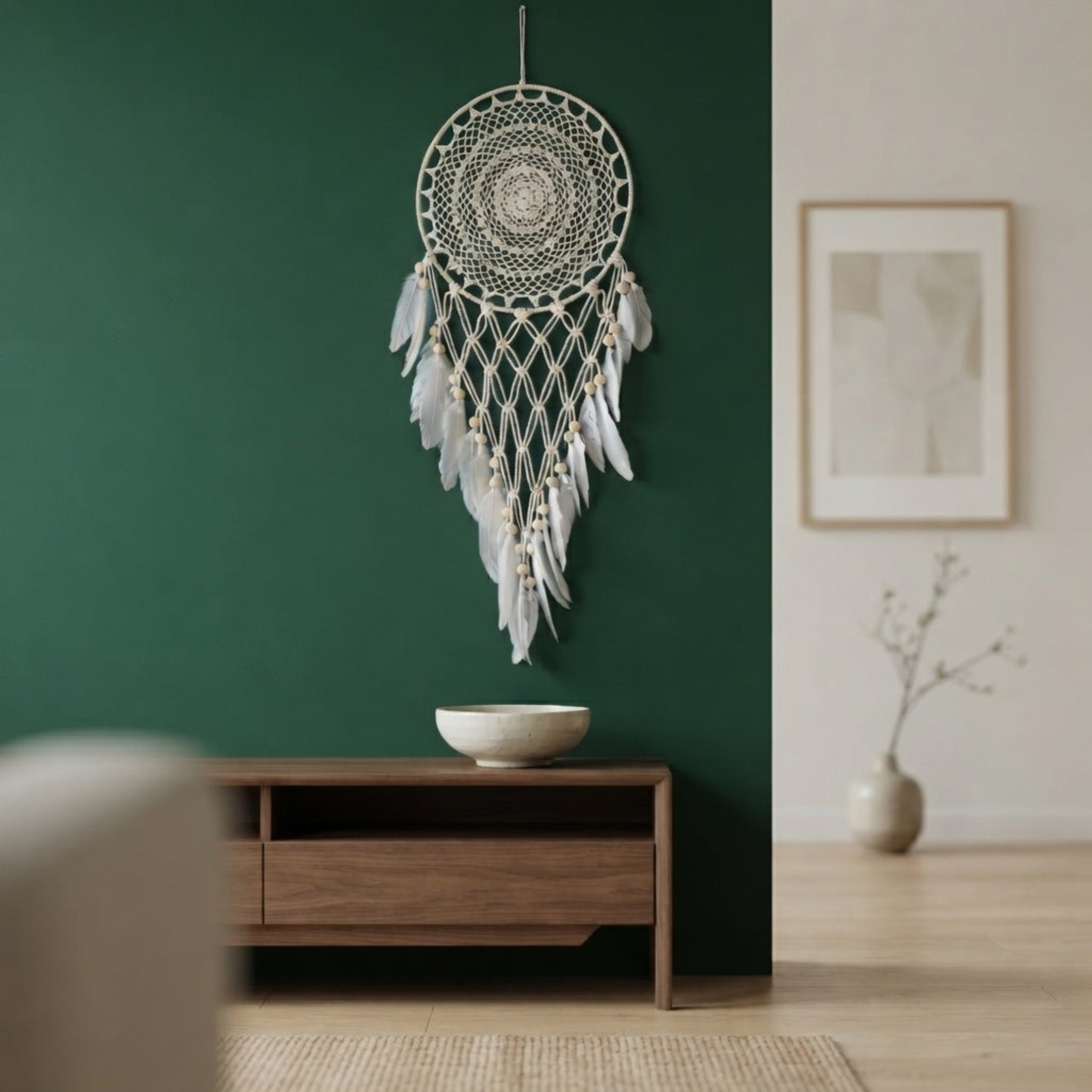 Boho macrame dreamcatcher with faux feather decor mounted on a deep green living room wall