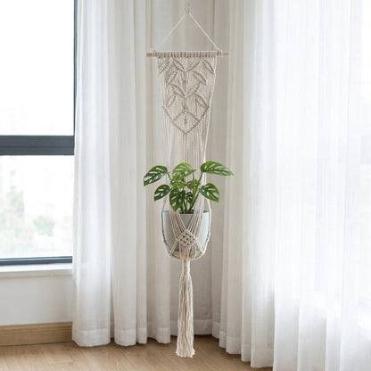 Beige cotton rope plant hanger with wooden dowel hanging near window in Scandinavian bedroom natural light